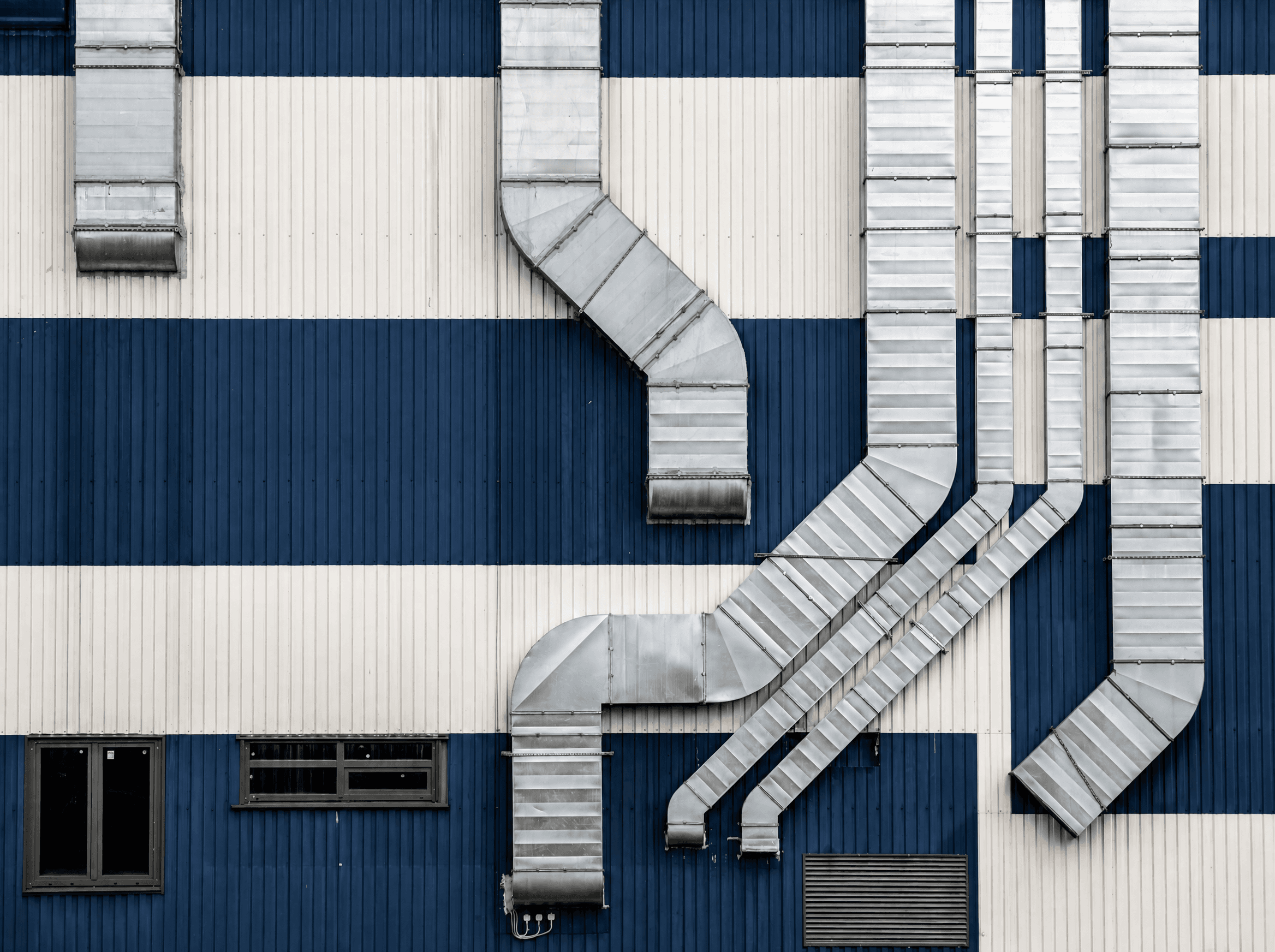 Silver metal ductwork running down the navy-and-cream striped wall of a commercial building
