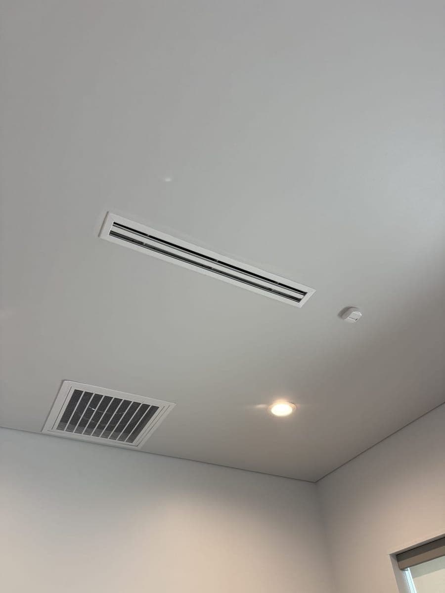 Finished white ceiling with a linear slot diffuser and a return grille