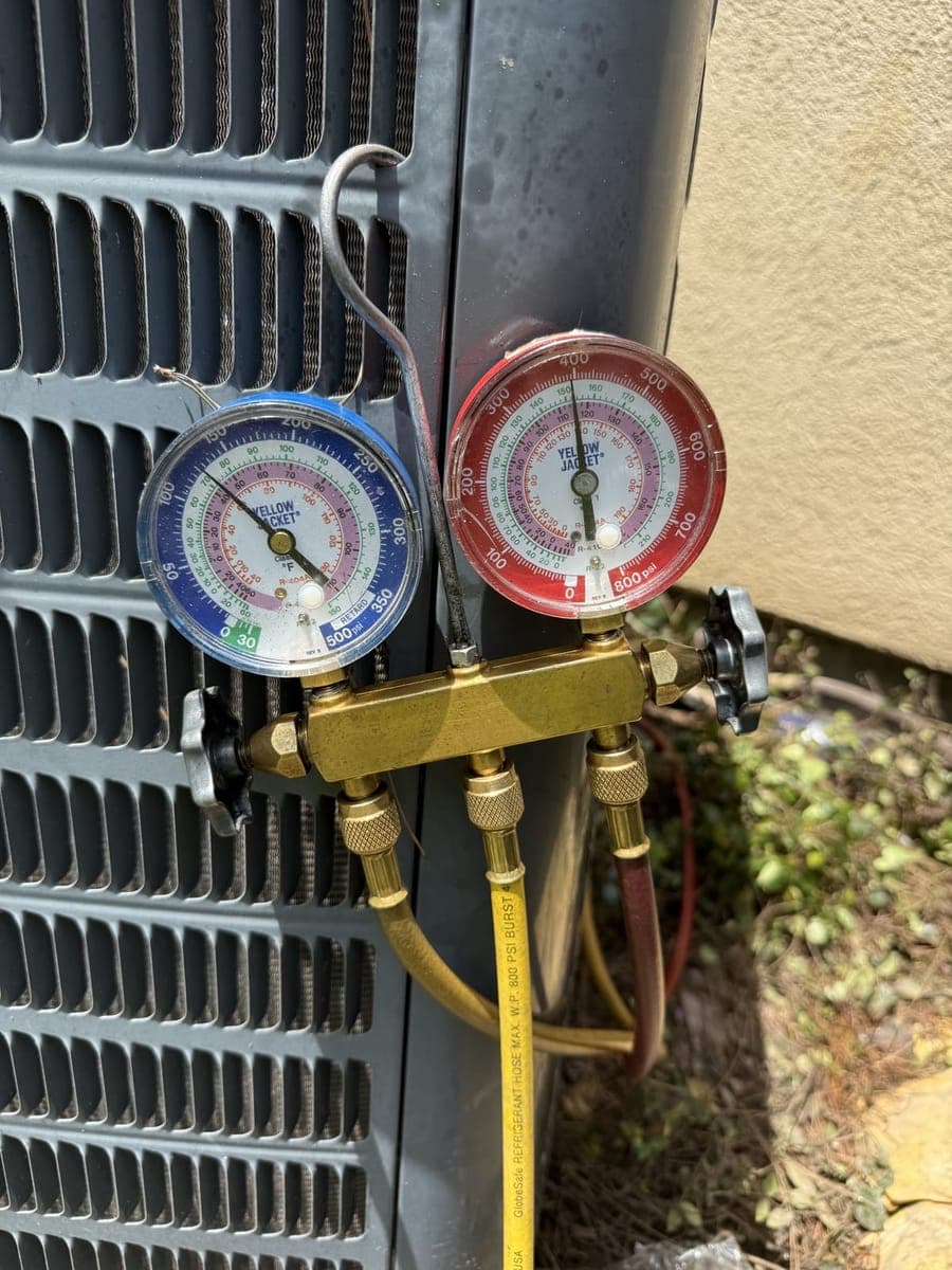Blue and red refrigerant gauges connected to an outdoor AC unit