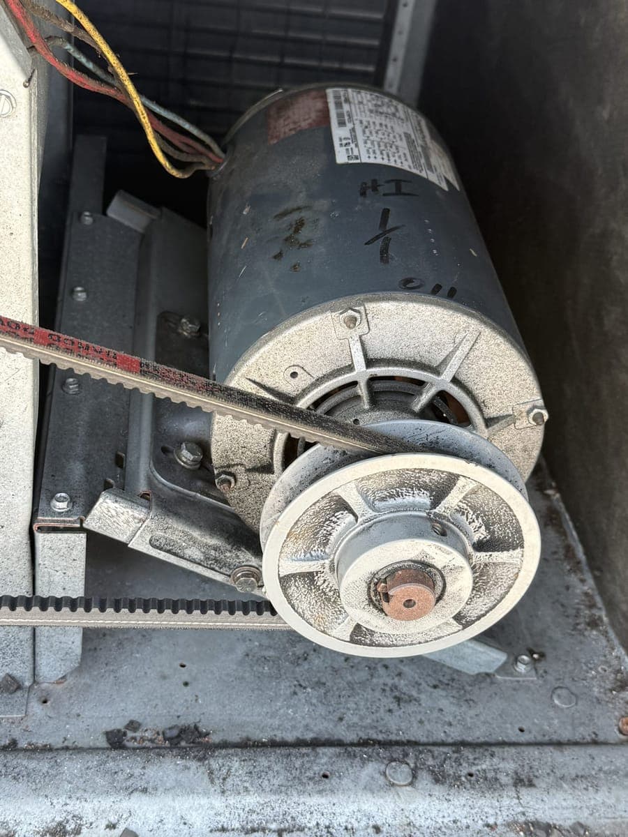 Belt-driven blower motor and pulley inside a rooftop unit