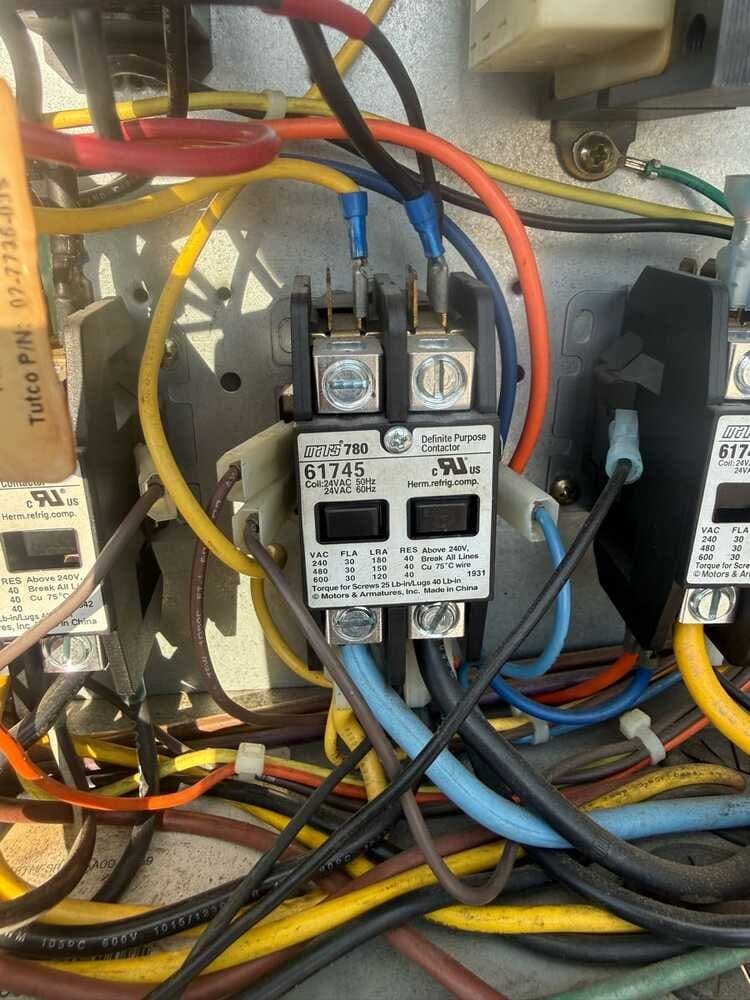 Close-up of contactors and color-coded wiring inside a rooftop AC unit