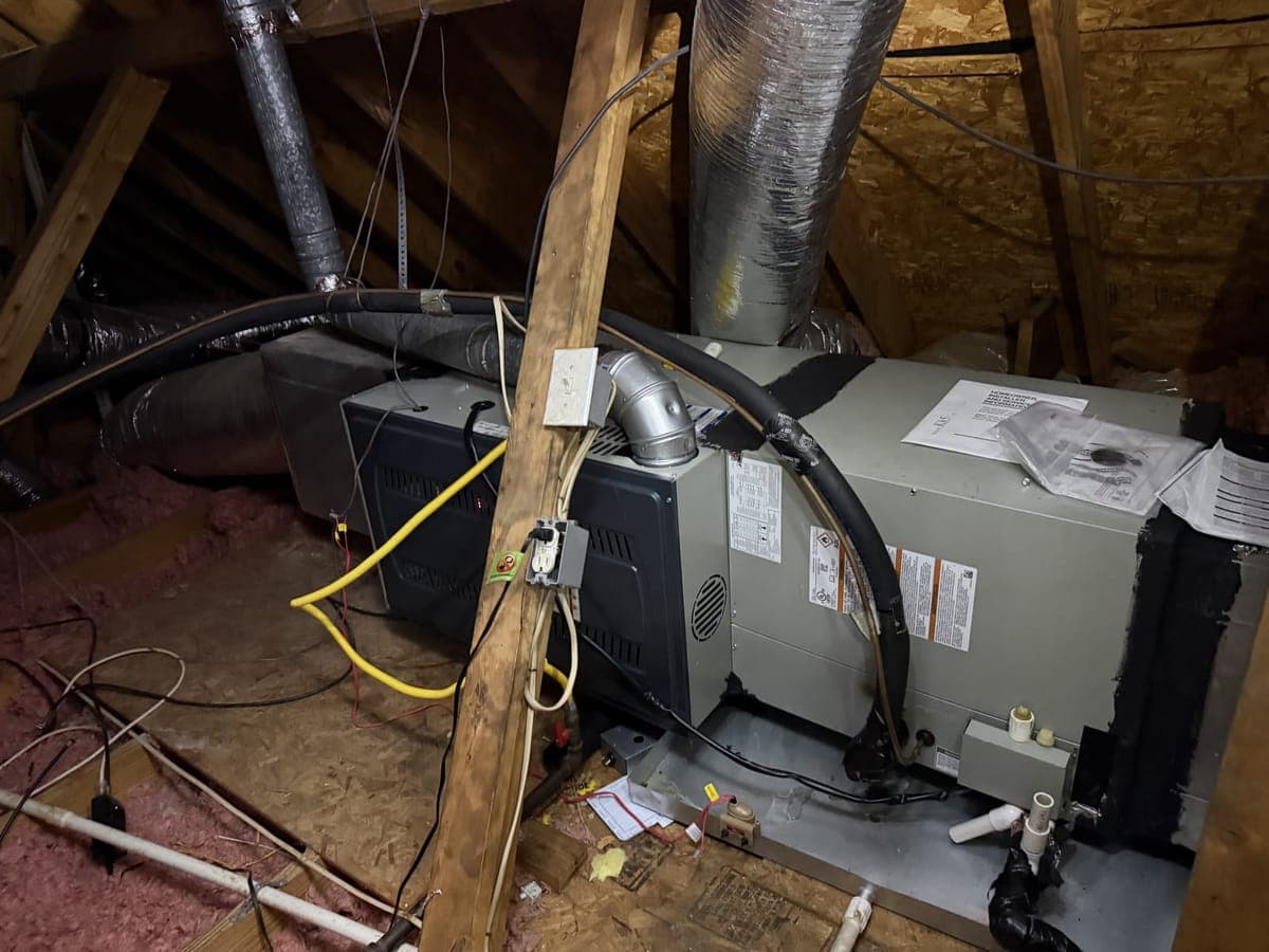 New indoor HVAC unit installed in an attic, with insulated ductwork and refrigerant lines connected